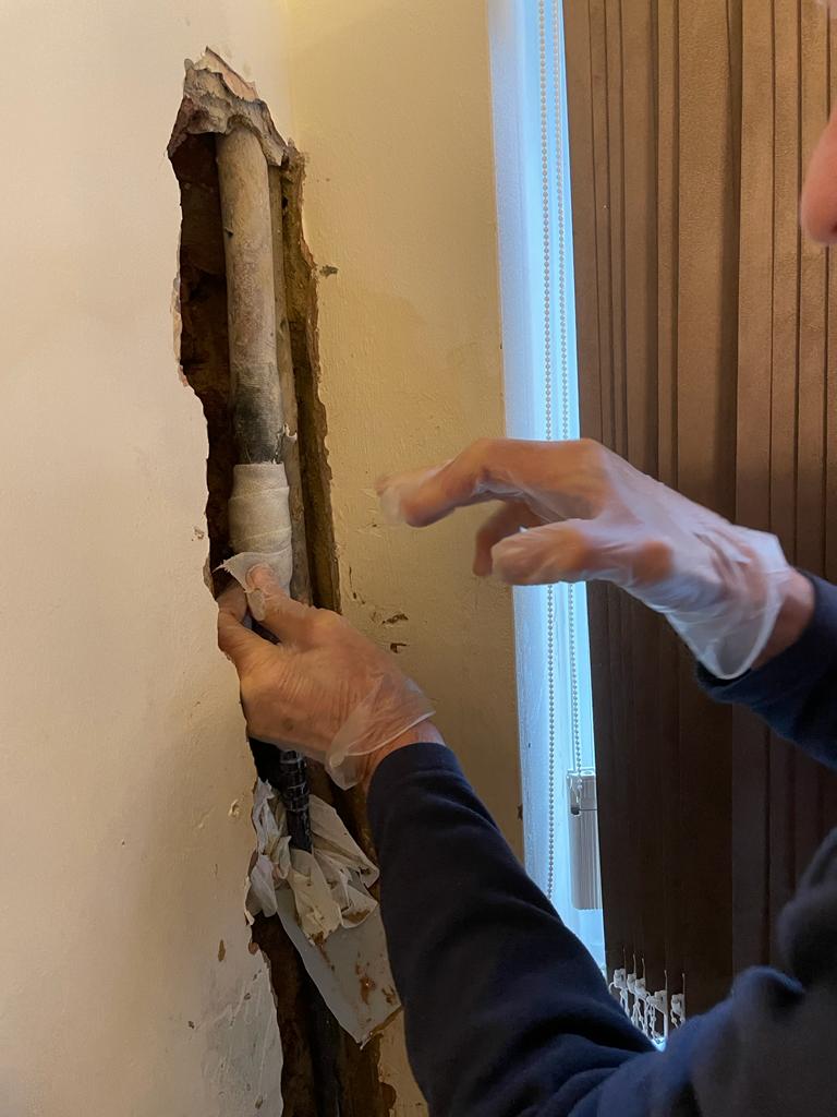 SylWrap HD Pipe Repair Bandage being applied to a lead water pipe leaking inside the wall of a home